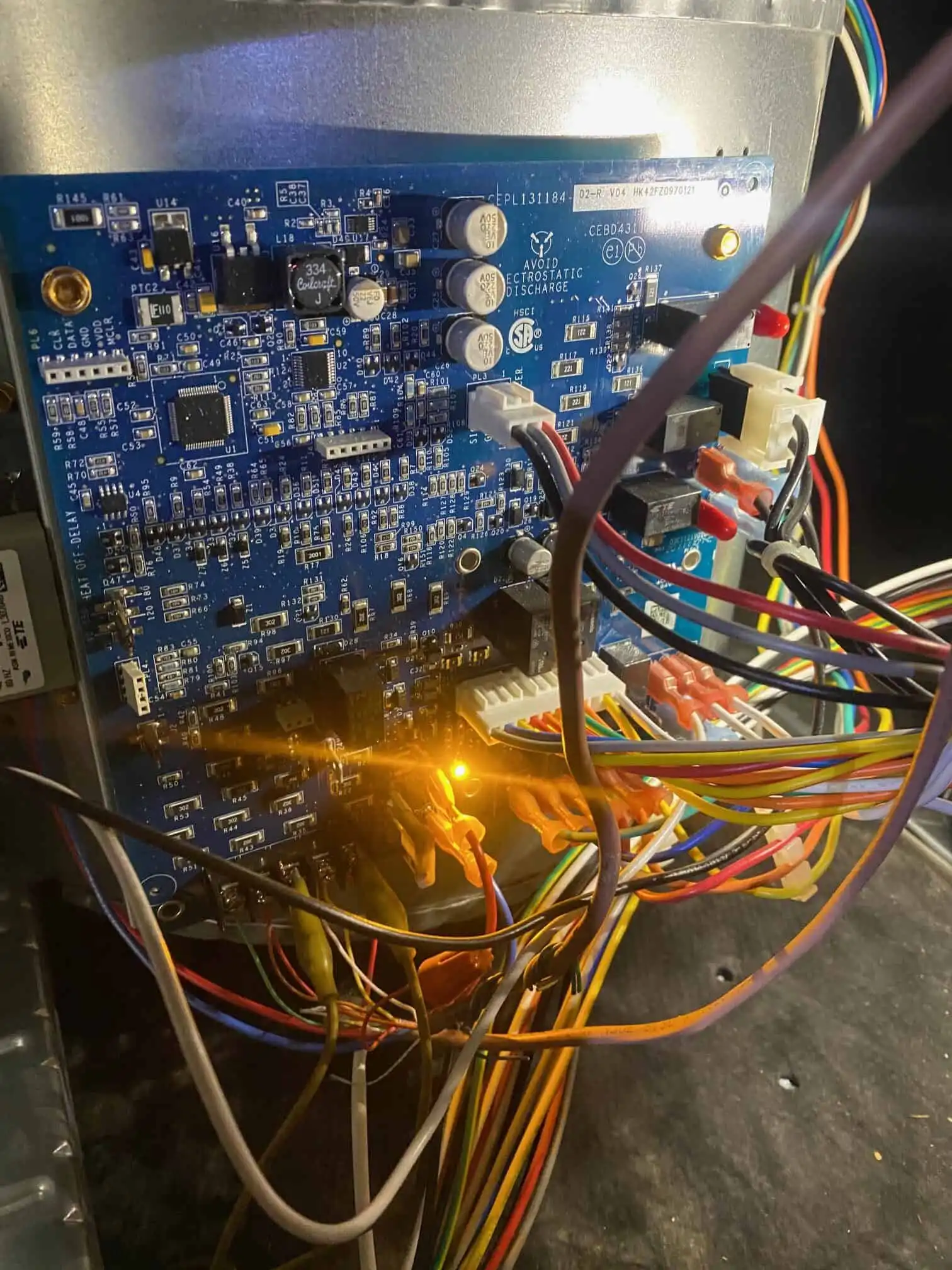 Close-up of an HVAC control board with wiring and indicator lights during diagnostic testing.