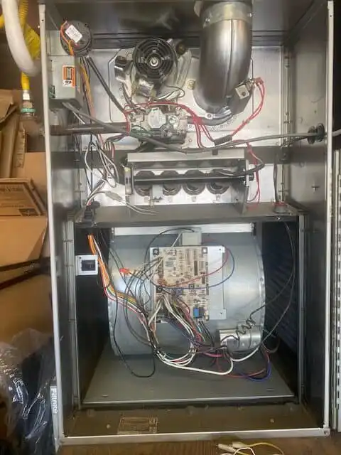 Upright gas furnace with its access panels removed, showing the draft inducer, gas valve, burners and blower compartment