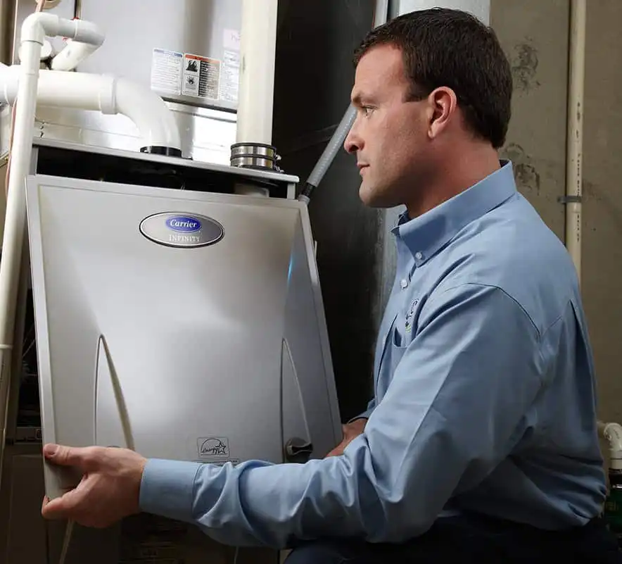 Clean energy HVAC technician inspecting a Carrier Infinity furnace in a residential home in Los Angeles.