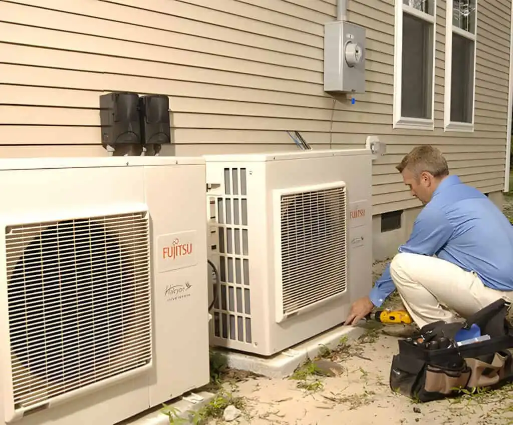 HVAC technician servicing Fujitsu outdoor air conditioning units at a residential property.