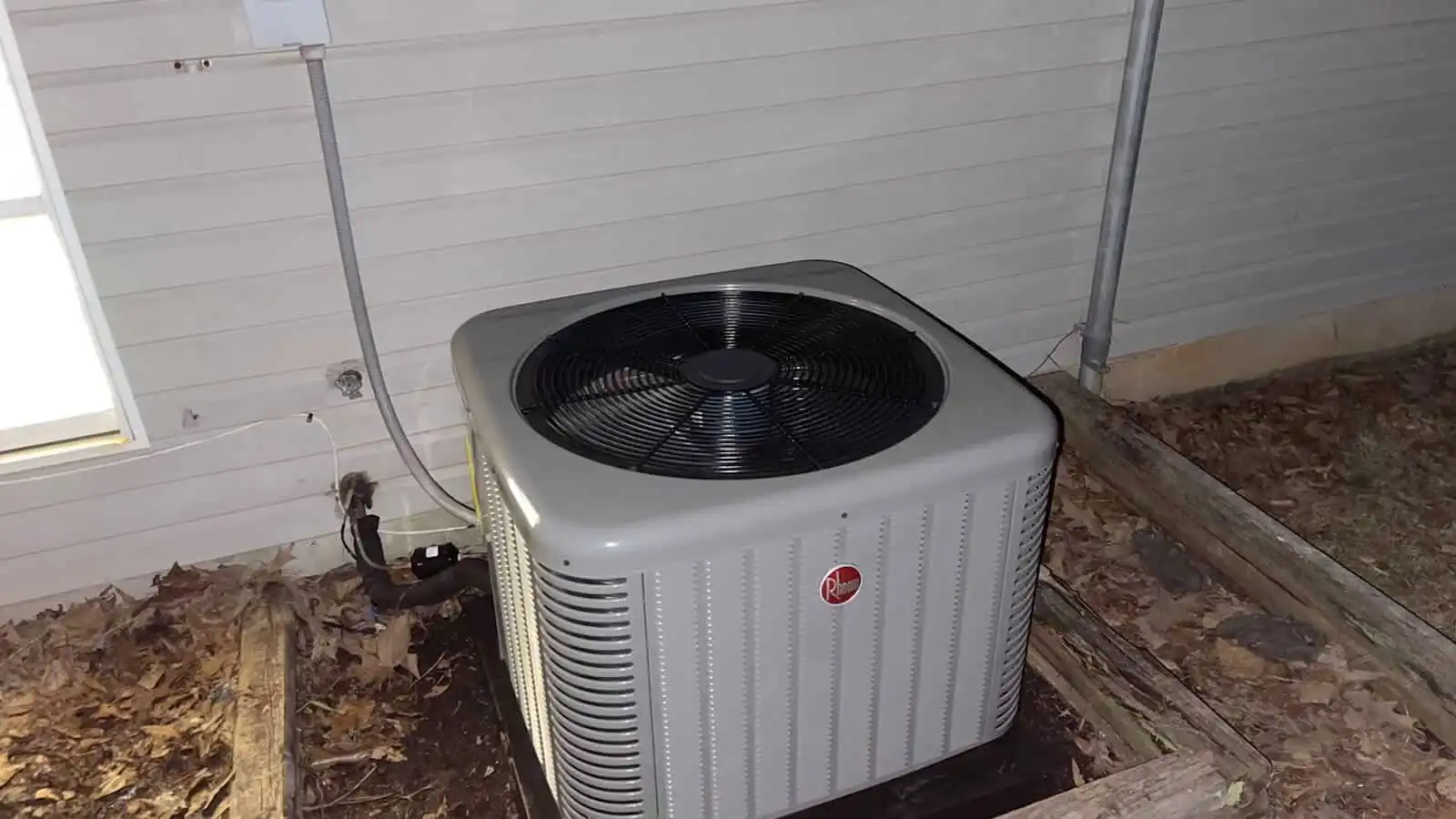 Air conditioning unit outside a house on a concrete pad.