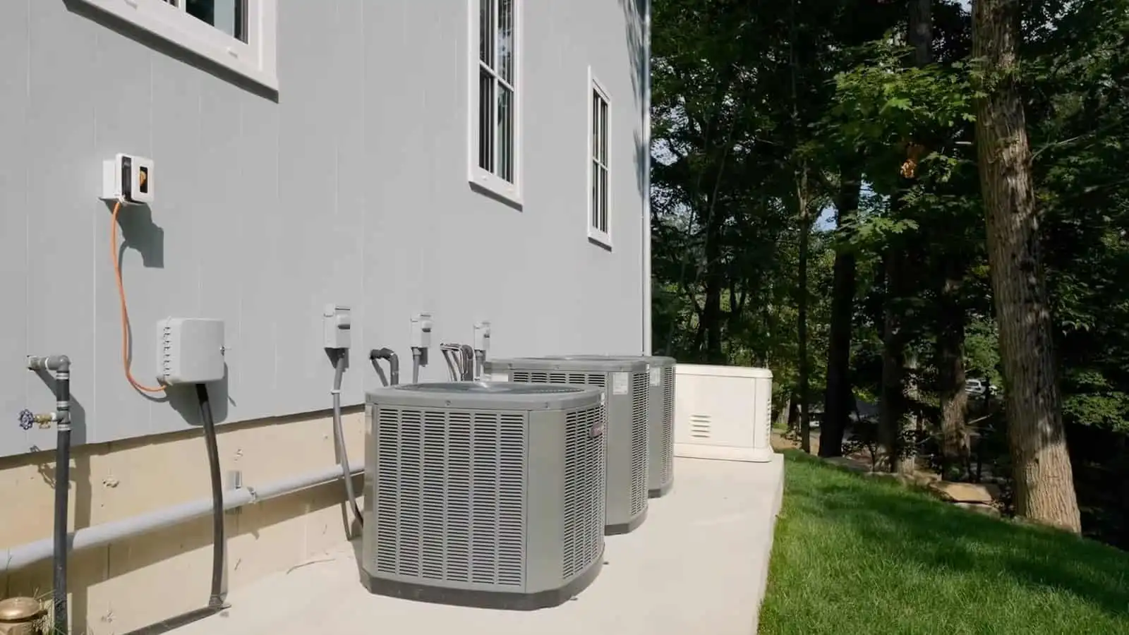 Air conditioning units installed outdoors on a concrete slab beside a house.