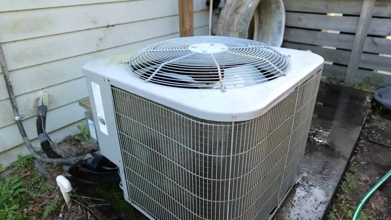 Air conditioning outdoor unit on a concrete pad outside a house.