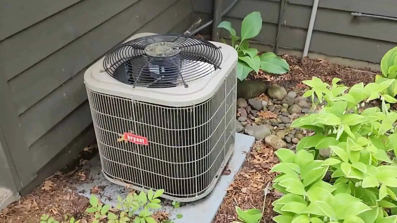 Outdoor air conditioning unit in a garden with plants and rocks.