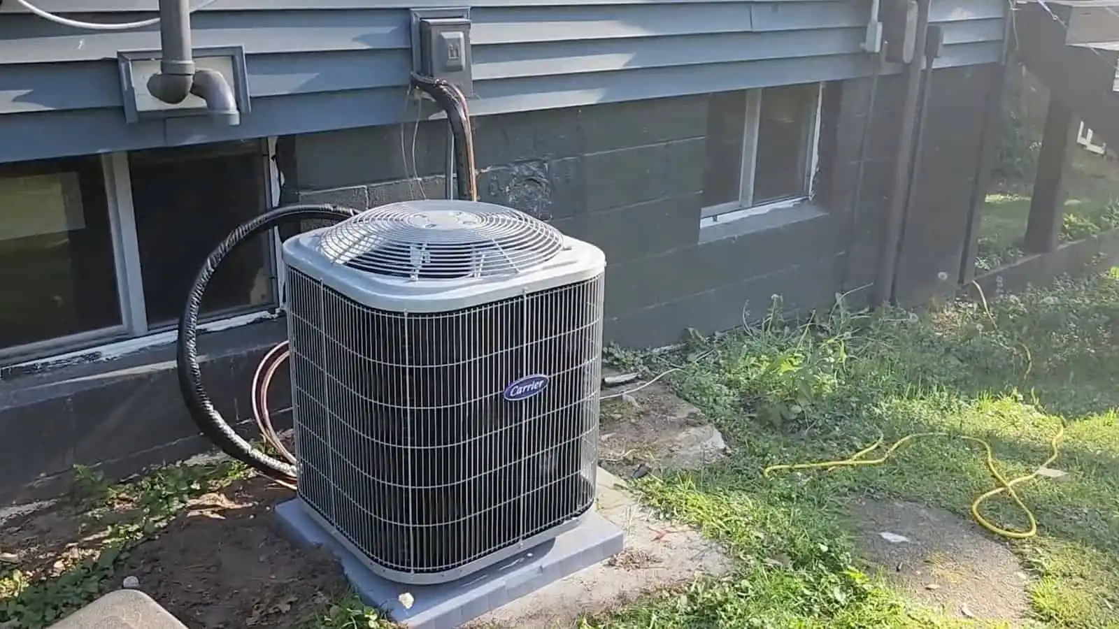 Outdoor air conditioning unit on a concrete pad beside a house.
