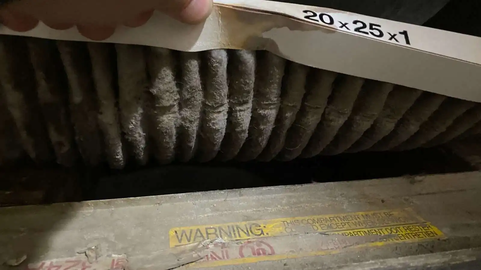 Technician holding a clogged air filter removed during HVAC service
