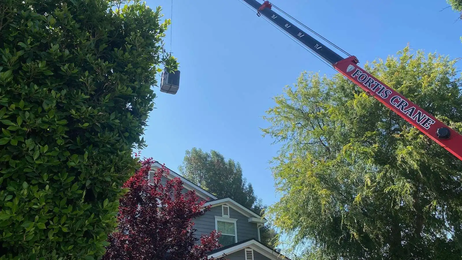 Crane setting a new AC system in place during a rooftop replacement