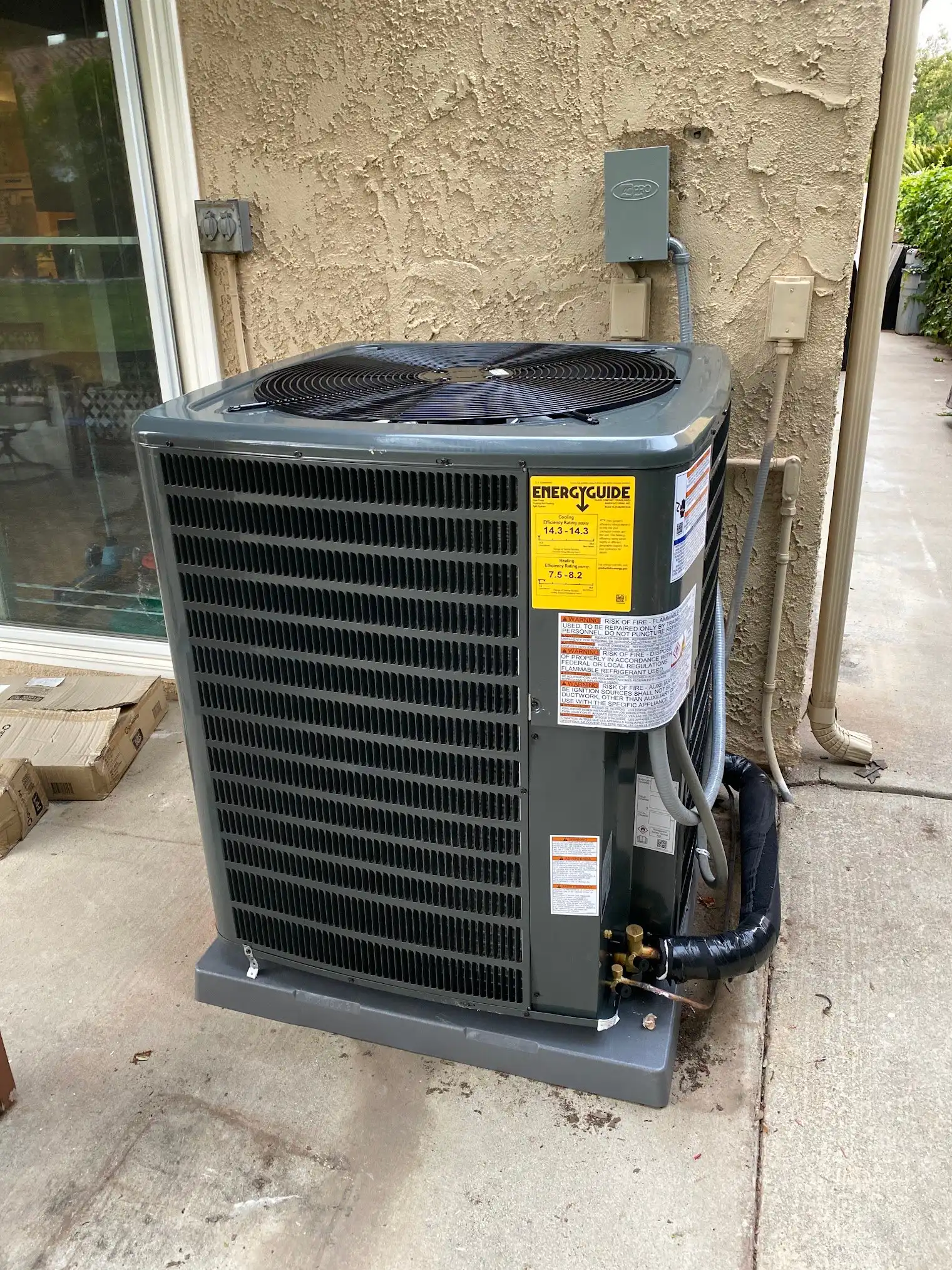 Central AC condenser installed on a level pad beside a stucco home