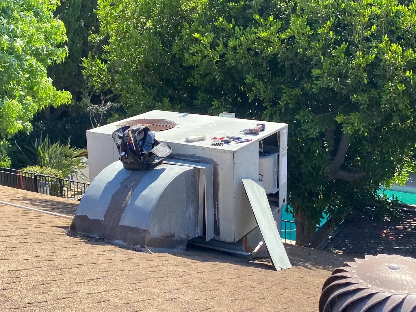 Aging rooftop package unit on a shingle roof, the kind of system where repair-versus-replace math matters