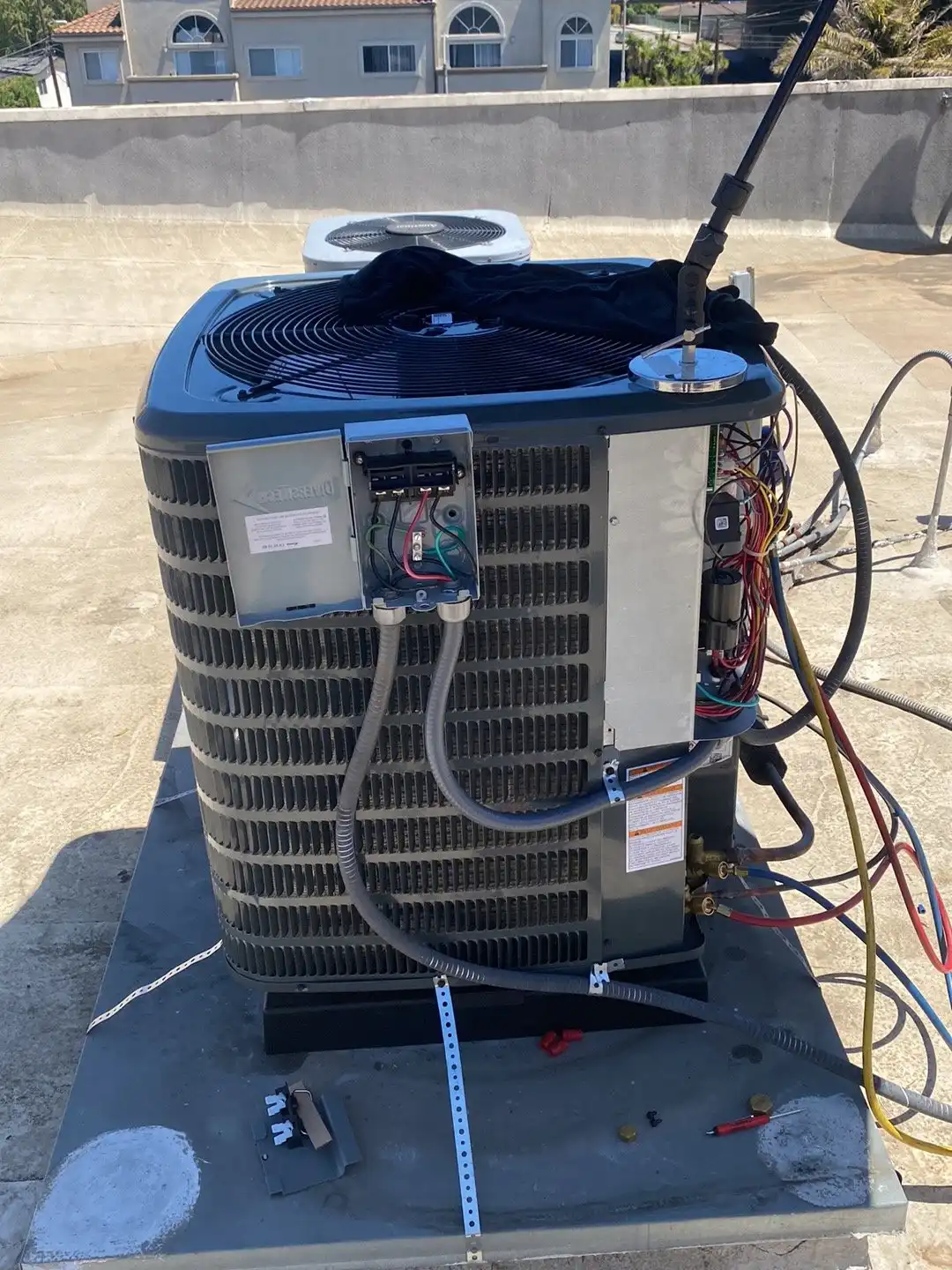 AC condenser with the service panel open and gauge hoses connected during a repair check