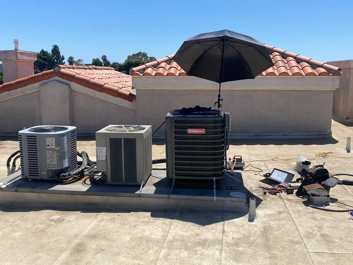 Three rooftop condensers with a technician shaded workstation set up to service them one after another