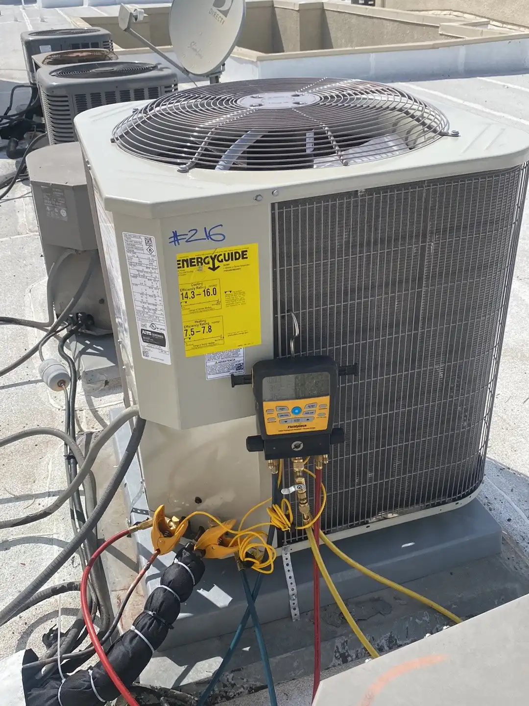 Digital manifold gauges connected to a numbered rooftop condenser, so readings are recorded against the right unit