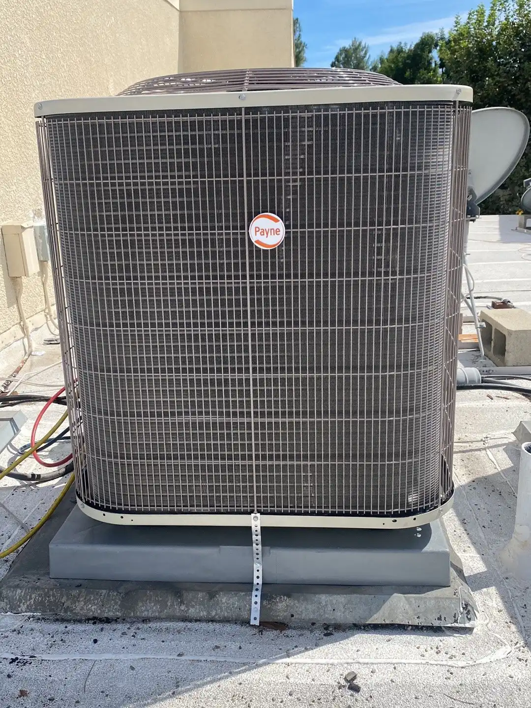 Payne AC condenser on a rooftop pad with its refrigerant lines and electrical disconnect