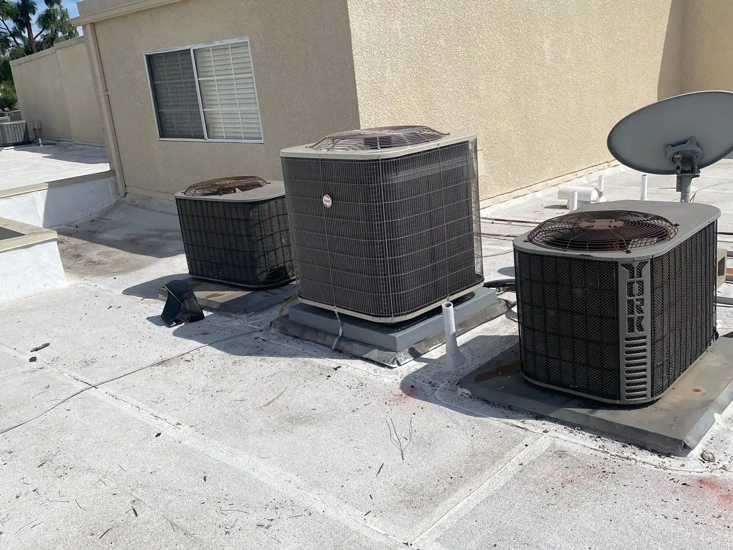Three condensers on the flat roof of a multi-unit residential building