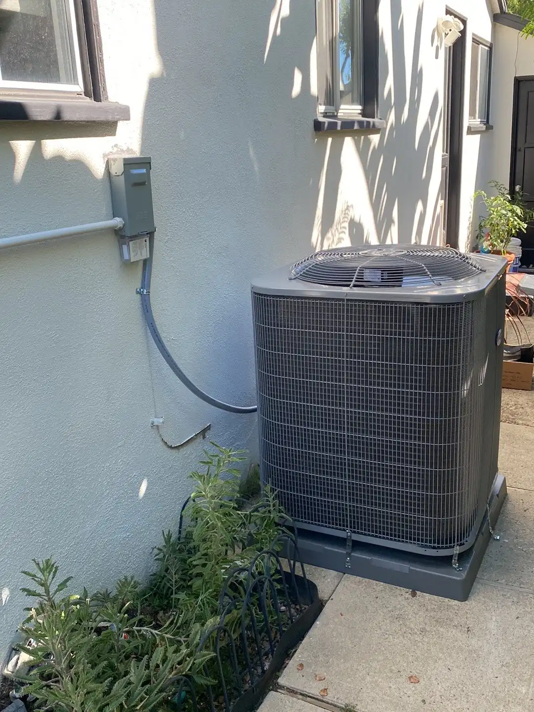 Central AC condenser on a pad along the side yard of a stucco home