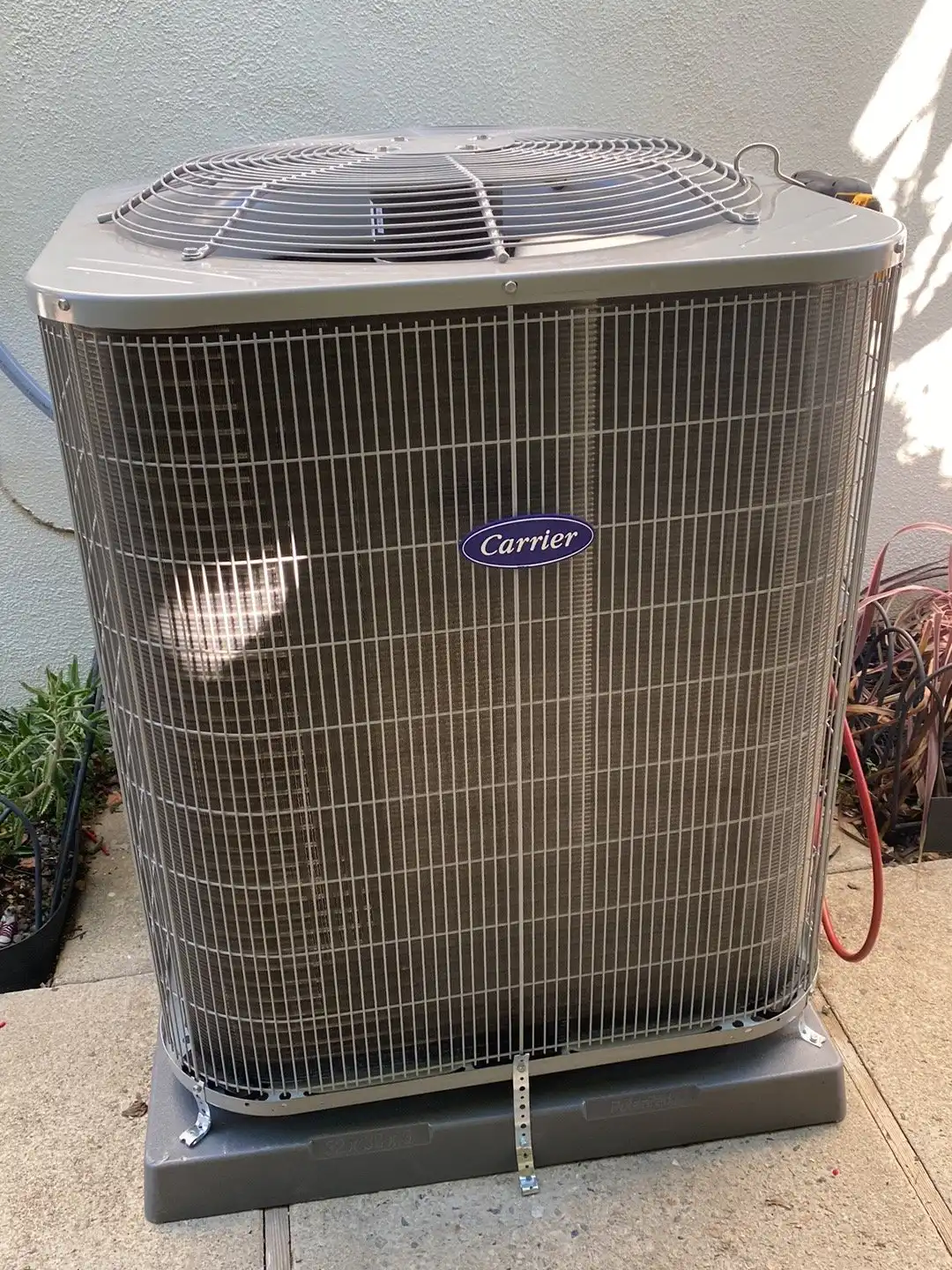 Carrier central AC condenser on a pad beside a home, typical of the split systems we repair in Chatsworth